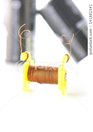 A coil and a dry cell battery are photographed against a white background. A coil and a dry cell battery are photographed against a white background. 141881341