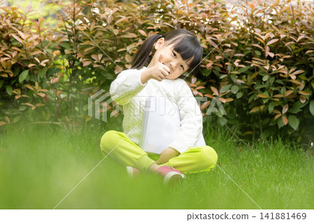 Proud little girl holding book and showing thumb up sign, education success concept. Proud little girl holding book and showing thumb up sign, education success concept. 141881469