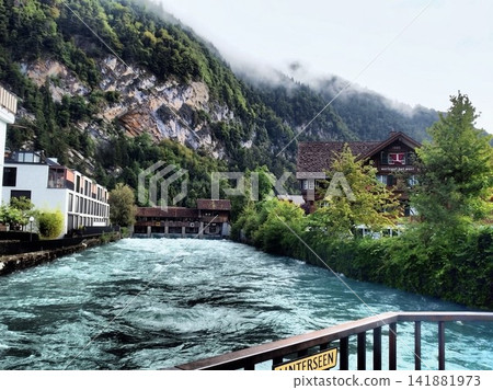 The Aare River flowing through Unterseen, Switzerland, with traditional wooden locks and mountain scenery. The Aare River flowing through Unterseen, Switzerland, with traditional wooden locks and mountain scenery. 141881973