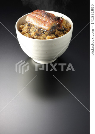 A piping hot mini eel rice bowl photographed alone against a black background. A piping hot mini eel rice bowl photographed alone against a black background. 141881999