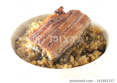 A piping hot mini eel rice bowl photographed alone against a white background. A piping hot mini eel rice bowl photographed alone against a white background. 141882137