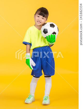 Captured from a profile perspective, the same East Asian girl in full soccer kit (jersey, shorts, socks, shoes) wears a bright green goalkeeper glove on one hand and balances on one leg Captured from a profile perspective, the same East Asian girl in full soccer kit (jersey, shorts, socks, shoes) wears a bright green goalkeeper glove on one hand and balances on one leg 141882334
