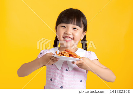 Happy child showing a piece of dehydrated fruit snack while holding a plate Happy child showing a piece of dehydrated fruit snack while holding a plate 141882368