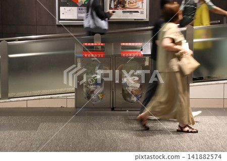 A trash can with a transparent interior; a trash can at a train station. A trash can with a transparent interior; a trash can at a train station. 141882574