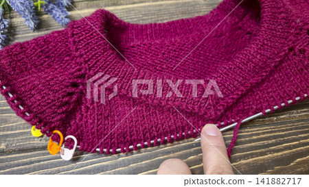 Knitted sweater collar in progress, using knitting needles and stitch markers. Knitted sweater collar in progress, using knitting needles and stitch markers. 141882717
