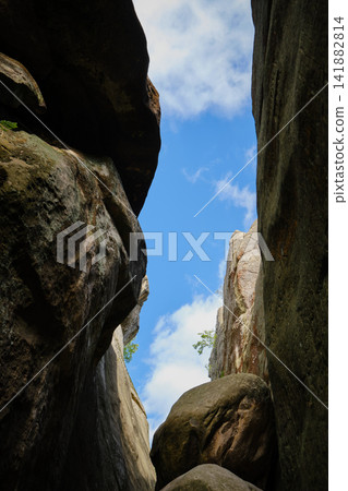 massive rock walls under a bright blue sky with fluffy white clouds massive rock walls under a bright blue sky with fluffy white clouds 141882814