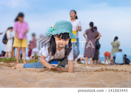 Asian Little Girl Playing With Sand on Beach During Summer Vacation Asian Little Girl Playing With Sand on Beach During Summer Vacation 141883445