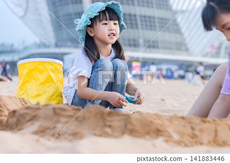 Asian Little Girl Playing With Sand on Beach During Summer Vacation Asian Little Girl Playing With Sand on Beach During Summer Vacation 141883446