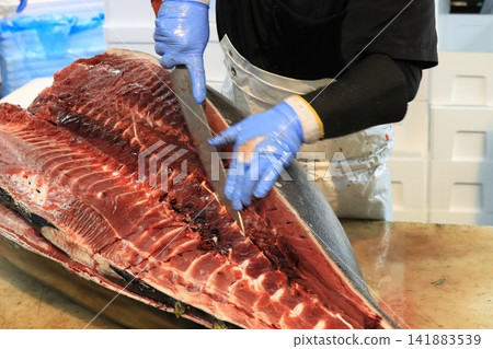 Raw tuna being filleted by a tuna craftsman Raw tuna being filleted by a tuna craftsman 141883539