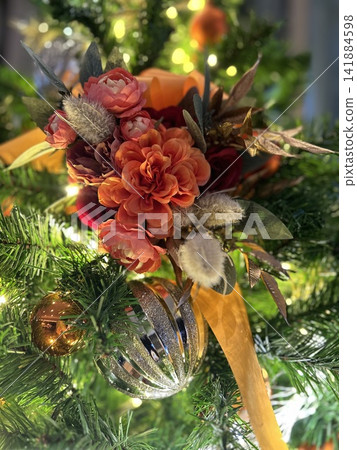 A close-up of a beautiful Christmas tree adorned with warm floral decorations and sparkling ornaments. A close-up of a beautiful Christmas tree adorned with warm floral decorations and sparkling ornaments. 141884598
