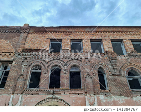 Historic red brick industrial building with decorative arches showing signs of decay in abandoned condition Historic red brick industrial building with decorative arches showing signs of decay in abandoned condition 141884767