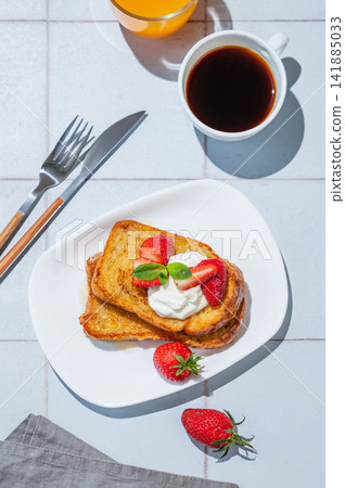Brioche toasts with strawberries and whipped cream, drizzled with honey on a plate Brioche toasts with strawberries and whipped cream, drizzled with honey on a plate 141885033