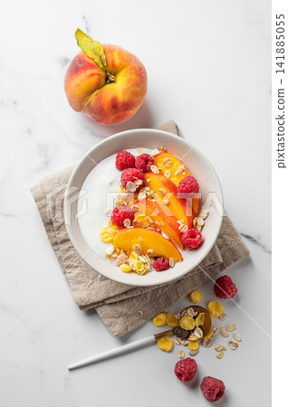 Natural greek yogurt with muesli, raspberry, peach and honey in a bowl on a marble background Natural greek yogurt with muesli, raspberry, peach and honey in a bowl on a marble background 141885055