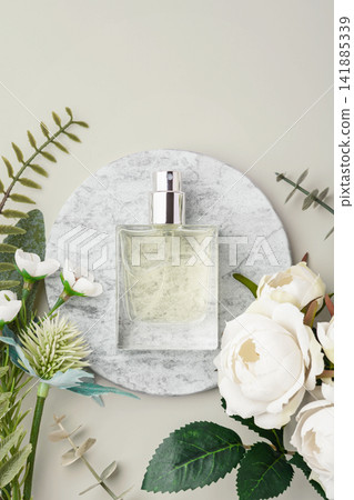 Glass perfume bottle on marble tray with white roses and green leaves decoration on beige background. copy space 141885339