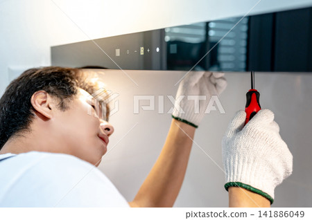 Asian male maintenance worker using screwdriver fixing light on cooker hood Asian male maintenance worker using screwdriver fixing light on cooker hood 141886049