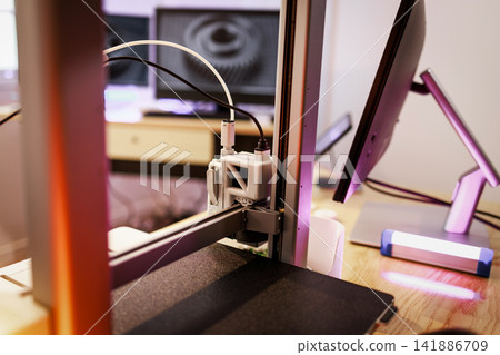 Close-up of a 3d printer working near a computer monitor in a modern workspace Close-up of a 3d printer working near a computer monitor in a modern workspace 141886709