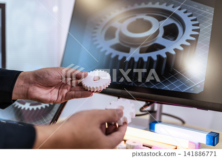 Hands holding a small 3d printed gear in front of a computer screen a larger gear design, with a focus on engineering and product development Hands holding a small 3d printed gear in front of a computer screen a larger gear design, with a focus on engineering and product development 141886771