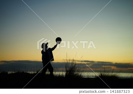 Silhouette of Child Balancing Ball at Sunset Silhouette of Child Balancing Ball at Sunset 141887323