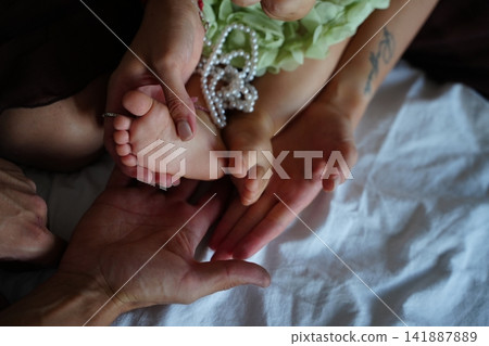 Hands Holding Baby's Feet with Love and Care 141887889
