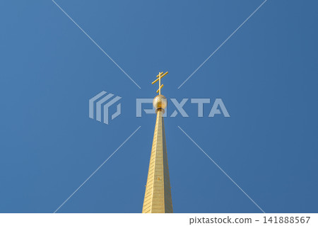 Golden spire reaching towards the sky above the Cathedral of the Assumption in Tula Russia reflecting sunlight in a serene blue atmosphere Golden spire reaching towards the sky above the Cathedral of the Assumption in Tula Russia reflecting sunlight in a serene blue atmosphere 141888567