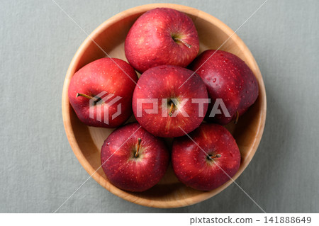 Fresh red apples fruit (Red Delicious) in a wooden bowl on cotton fabric background, Top view Fresh red apples fruit (Red Delicious) in a wooden bowl on cotton fabric background, Top view 141888649