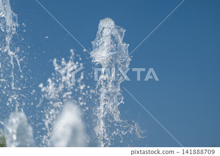 Dancing water jets create a mesmerizing display under a clear blue sky 141888709