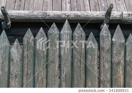 Wooden fence with pointed tops showcases rustic craftsmanship and structure in an outdoor setting under bright sunlight 141888931