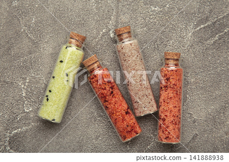 Set of different Himalayan salt in glass bottle with wooden cap on grey concrete background Set of different Himalayan salt in glass bottle with wooden cap on grey concrete background 141888938