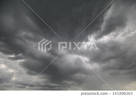 Dark clouds swirl ominously above hinting at an approaching storm during late afternoon in the sky Dark clouds swirl ominously above hinting at an approaching storm during late afternoon in the sky 141890263