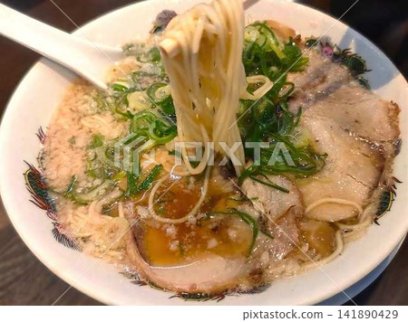 濃鬱的豬骨湯拉麵,配上叉燒肉,用筷子夾起食用。 濃鬱的豬骨湯拉麵,配上叉燒肉,用筷子夾起食用。 141890429