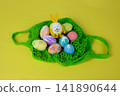 Easter eggs with bunny ears are placed on a yellow background in a green grid. Easter concept 141890644