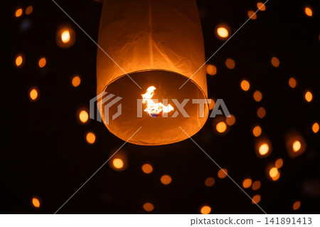 Sky lantern floating in the dark night sky, Tourist floating sky lanterns, Sky lanterns floating on night of Yi Peng, Loy Krathong Festival or Yi Peng Festival in Chiang Mai Thailand. Sky lantern floating in the dark night sky, Tourist floating sky lanterns, Sky lanterns floating on night of Yi Peng, Loy Krathong Festival or Yi Peng Festival in Chiang Mai Thailand. 141891413