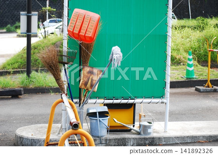 A set of cleaning tools lined up in front of the fence A set of cleaning tools lined up in front of the fence 141892326