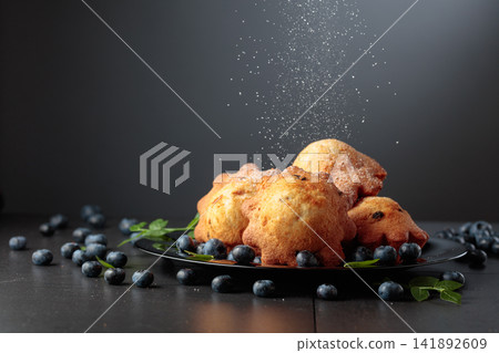Freshly baked blueberry muffins are dusted with icing sugar. Freshly baked blueberry muffins are dusted with icing sugar. 141892609