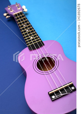 Four string ukulele guitar on blue background Four string ukulele guitar on blue background 141892678