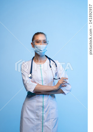 Medical professional holding syringe, wearing face mask and goggles, providing healthcare and protection from viruses Medical professional holding syringe, wearing face mask and goggles, providing healthcare and protection from viruses 141892957