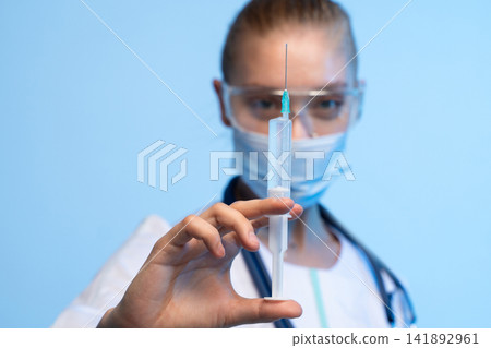Healthcare worker holding a syringe, preparing for vaccination or injection, representing medical care and disease prevention Healthcare worker holding a syringe, preparing for vaccination or injection, representing medical care and disease prevention 141892961