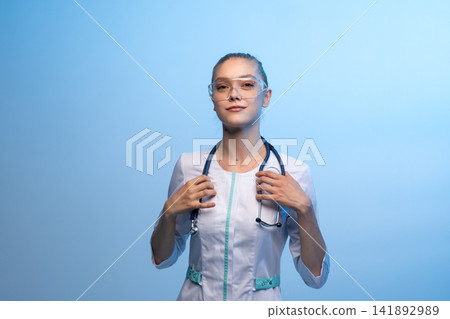 Young woman medical professional wearing safety glasses and stethoscope Young woman medical professional wearing safety glasses and stethoscope 141892989