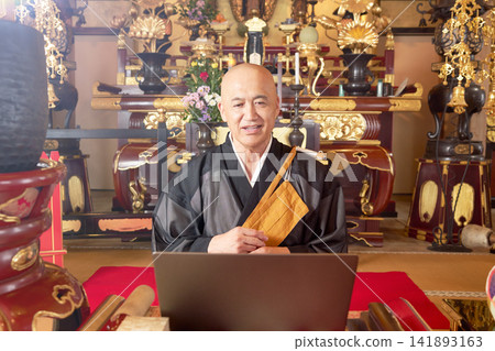 A monk making a video call in the main hall of a temple. A monk making a video call in the main hall of a temple. 141893163