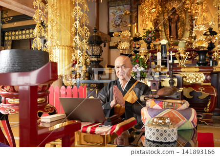 A monk clasps his hands together in front of a laptop computer. A monk clasps his hands together in front of a laptop computer. 141893166