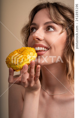 Young woman enjoying yellow glazed donut, feeling happy and craving sweet dessert for snack Young woman enjoying yellow glazed donut, feeling happy and craving sweet dessert for snack 141893196