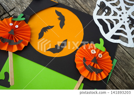 DIY Halloween pumpkin props made of pleated orange paper laid on a rustic wooden table DIY Halloween pumpkin props made of pleated orange paper laid on a rustic wooden table 141893203