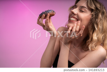 Happy young woman enjoying a sweet eclair with closed eyes, feeling delight and pleasure from dessert Happy young woman enjoying a sweet eclair with closed eyes, feeling delight and pleasure from dessert 141893213