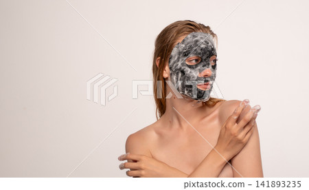 Woman enjoying a beauty routine, applying a charcoal oxygen bubble mask for deep skin cleansing and refreshing Woman enjoying a beauty routine, applying a charcoal oxygen bubble mask for deep skin cleansing and refreshing 141893235