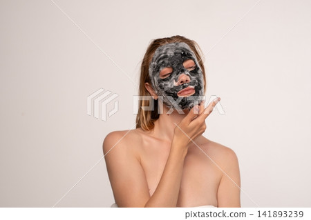 Woman applying purifying charcoal bubble mask for glowing skin, engaging in self-care spa treatment Woman applying purifying charcoal bubble mask for glowing skin, engaging in self-care spa treatment 141893239