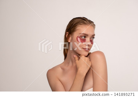 Woman applying hydrogel eye patches, performing a beauty ritual for delicate under-eye skin, achieving a fresh look Woman applying hydrogel eye patches, performing a beauty ritual for delicate under-eye skin, achieving a fresh look 141893271