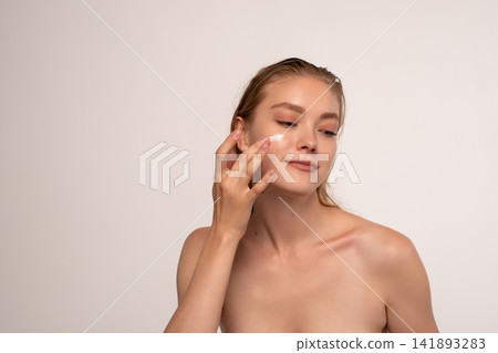 Young woman applying face cream to glowing skin, enjoying a regular skincare routine for beauty and wellness Young woman applying face cream to glowing skin, enjoying a regular skincare routine for beauty and wellness 141893283