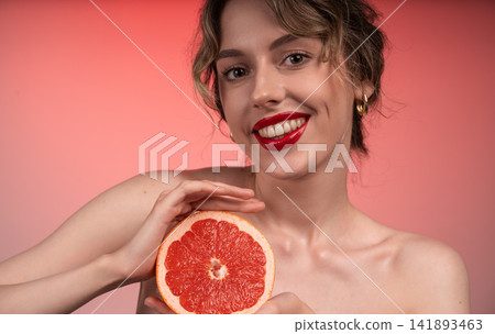 Woman smiling and holding half a red grapefruit, embracing natural beauty and fresh, healthy skin care Woman smiling and holding half a red grapefruit, embracing natural beauty and fresh, healthy skin care 141893463