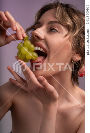 Young woman enjoying fresh green grapes, symbolizing healthy eating, natural beauty, and a joyful lifestyle Young woman enjoying fresh green grapes, symbolizing healthy eating, natural beauty, and a joyful lifestyle 141893465