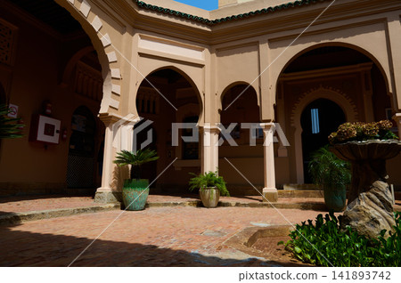 Sunlit Moorish courtyard with arches, columns and fountain in Tangier Morocco 141893742